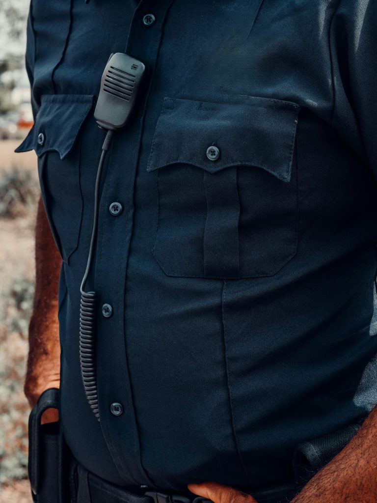 Vista detallada del uniforme de un agente de policía, donde se aprecian la placa y el equipo de radio.